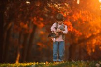 Boy standing outdoor coccolando un pollo, Stati Uniti — Foto stock