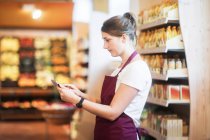 Assistente de supermercado verificando produtos usando um tablet digital — Fotografia de Stock