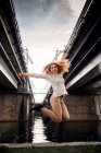 Femme sautant dans les airs près d'une rivière, Belgique — Photo de stock