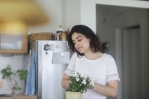 Femme s'occupant d'une plante en pot dans sa cuisine — Photo de stock