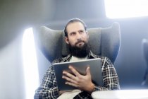 Чоловік сидить у кріслі за допомогою цифрового планшета — стокове фото