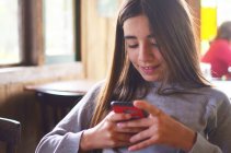Дівчина-підліток дивиться на свій мобільний телефон — стокове фото