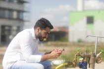 Чоловік сидить на вулиці, використовуючи свій мобільний телефон — стокове фото