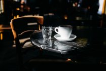 Primo piano di una tazza di caffè e un bicchiere d'acqua su un tavolo — Foto stock