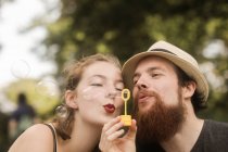 Paar sitzt in einem Park und hält einen Blasenstab, der Blasen pustet — Stockfoto