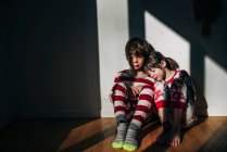 Irmão e irmã sentados no chão de pijama — Fotografia de Stock