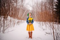 Ragazza in piedi nella neve che tiene un mazzo di fiori — Foto stock