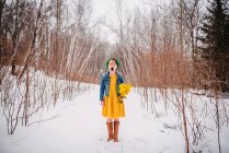 Ragazza in piedi nella neve che tiene un mazzo di fiori e sbadiglia — Foto stock