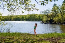 Menina em pé junto a um lago em seu traje de natação — Fotografia de Stock