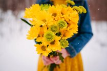 Close-up of a girl standing in the snow holding a bouquet of flowers — Stock Photo