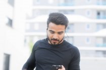 Homme écoutant de la musique sur son smartphone pendant son jogging — Photo de stock