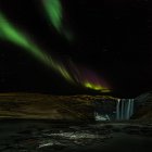 Scenic view of Northern lights over Skogarfoss waterfall, Southern Region, Iceland — Stock Photo