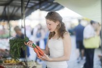 Frau kauft Möhren auf einem Wochenmarkt — Stockfoto
