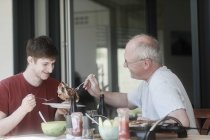 Дорослий батько, що обслуговує перегороджений стейк своєму синові — стокове фото