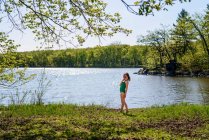 Fille debout près d'un lac dans son costume de natation — Photo de stock