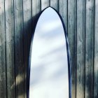 Primer plano de una tabla de surf apoyada en una valla de madera - foto de stock