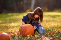 Mädchen schnitzt einen Halloween-Kürbis im Garten, USA — Stockfoto
