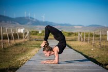 Женщина делает позу йоги скорпиона, проливной природный парк, тарифа, кадис, андалузия, Испания — стоковое фото