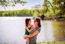 Madre in piedi vicino a un lago che porta sua figlia — Foto stock