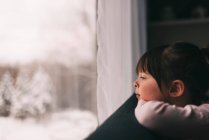 Девушка смотрит в окно зимой — стоковое фото
