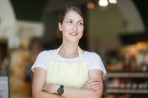 Retrato de uma assistente de vendas sorridente com os braços dobrados — Fotografia de Stock