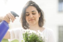 Woman spraying flowers with water in her garden — Stock Photo