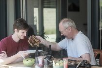 Взрослый отец подает своему сыну стейк на гриле — стоковое фото