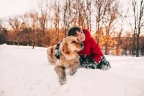 Ritratto di un ragazzo seduto sulla neve con il suo cane golden retriever — Foto stock