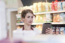 Помощник супермаркета проверяет продукты с помощью цифрового планшета — стоковое фото