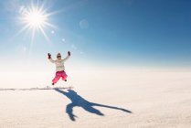 Menina pulando no ar em uma paisagem rural nevada — Fotografia de Stock