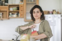 Mulher de pé na cozinha usando um moinho de café velho — Fotografia de Stock