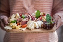 Girl holding a cheese and cured meat antipasto board — Stock Photo