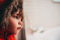 Мальчик в парке с мехом смотрит через стекло в дверь — стоковое фото