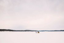 Family ice fishing on a frozen lake — Stock Photo