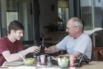 Adulto pai e filho sentado no terraço fazendo um brinde comemorativo — Fotografia de Stock