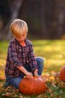 Lächelnder Junge schnitzt einen Halloween-Kürbis im Garten, Vereinigte Staaten — Stockfoto
