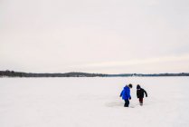 Two boys playing on a frozen lake — Stock Photo