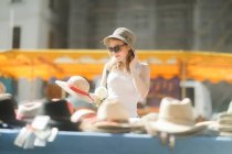 Женщина покупает шляпу на рынке — стоковое фото