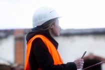 Portrait d'une femme sur un chantier écrit sur son presse-papiers — Photo de stock