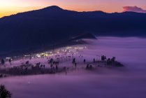 Low clouds engulfing Cemoro Lawang village during glorious sunrise at Bromo Tengger Semeru National Park in East Java Province, Indonesia. — Stock Photo