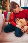 Boy cuddling his golden retriever dog on couch — Stock Photo