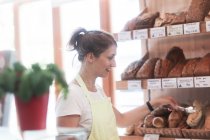 Assistente de vendas sorridente em uma padaria — Fotografia de Stock