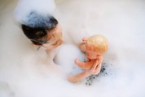 Jeune fille jouant dans un bain moussant — Photo de stock