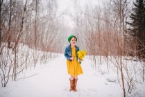 Ragazza in piedi nella neve che tiene un mazzo di fiori — Foto stock