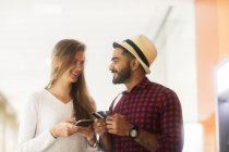 Портрет усміхненої пари, що тримає кредитні картки та використовує мобільний телефон — стокове фото