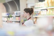 Asistente de tienda de supermercados comprobando productos usando una tableta digital - foto de stock