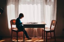 Хлопчик сидить за столом робить головоломку — стокове фото