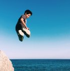 Junge springt am Strand in die Luft — Stockfoto