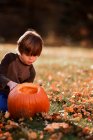Boy carving a Halloween pumpkin in the garden, United States — Stock Photo