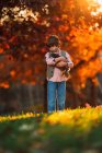 Мальчик, стоящий на улице и обнимающий курицу, США — стоковое фото